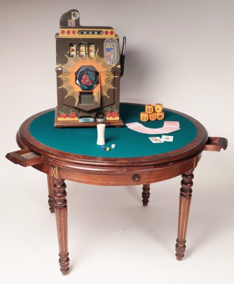 Victorian walnut felt top poker table with six drawers pictured with a vintage slot machine and carved bone dice cup