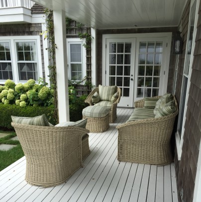 Wicker Sofa and Armchairs with Ottomans, with green striped upholstered cushions.