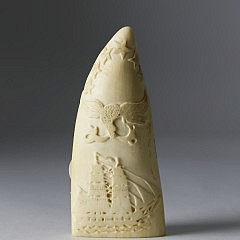 Whaleman Carved and Scrimshawed Sperm Whale Tooth, circa 1860, bas relief carved fully rigged bark on ocean with six stars and spread winged eagle with banner above. The reverse scrimshawed with monument of six American flags. Height 5 ¼ in. Provenance: Eldred’s