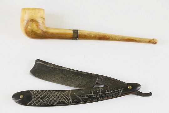 Two Sailor’s Accessories, 19th c., comprising a carved whale ivory pipe in two sections joined by a metal collar, and a straight edge with a baleen case engraved with whaling bark and fish, the steel edge by Hargreaves Smith & Co. Imperial Razor Sheffield